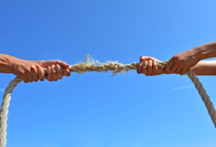 Teenagers hands playing tug-of-war with used rope